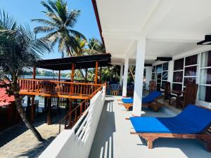 a porch of a house with blue chairs and palm trees at Luthmin River View Hotel in Alutgama