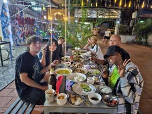 a group of people sitting around a table eating food at Apatuxay Vientiane Hostel in Vientiane