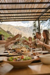 a group of people holding up their wine glasses at a table at Earth Tones Tiny Homes & Suites in Ollantaytambo