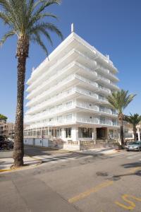 un grande edificio bianco con palme di fronte di Hotel Sultán a Can Picafort