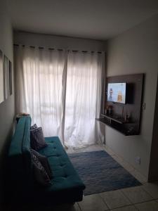 a living room with a green couch in front of a window at Aconchego II in Juiz de Fora