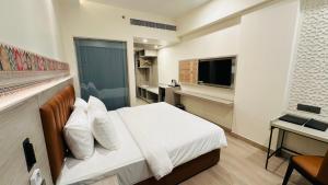 a bedroom with a bed and a desk and a television at Regenta Central Jaipur in Jaipur