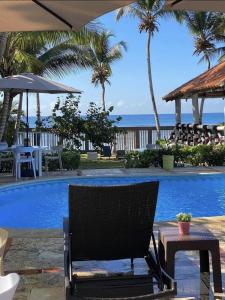 a chair next to a swimming pool with palm trees at franchecis hostal cerca del mar in Juan Dolio