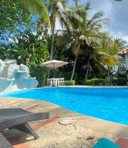 a swimming pool with a table and an umbrella at franchecis hostal cerca del mar in Juan Dolio +4 photos
