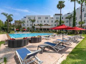 a pool with chairs and umbrellas next to a hotel at Ibis Fes in Fez