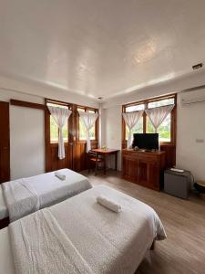 a hotel room with two beds and a television at Pahiluna Guesthouse in Panglao Island