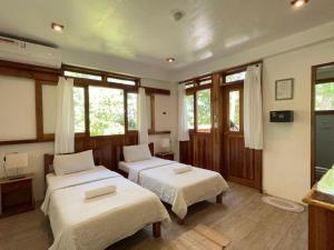 two beds in a room with windows at Pahiluna Guesthouse in Panglao Island