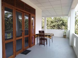 a dining room with a table and chairs on a porch at Wijaya Garden Hotel in Anuradhapura +1 photo