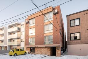 a yellow car parked in front of a brick building at Rafaye N16 in Sapporo
