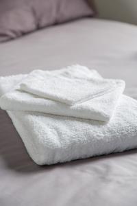 a stack of white towels sitting on a bed at The Pearl in Vitry-sur-Seine