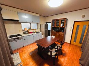 a kitchen with a wooden table and a wooden floor at MIYABI stay house in Tamana