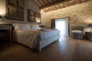 een slaapkamer met een groot bed en een bakstenen muur bij Villa Anitori Prestige Relais & Spa in Loro Piceno