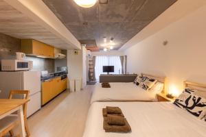 two beds in a small room with a kitchen at Rafaye N16 in Sapporo
