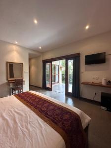 a bedroom with a large bed and a television at Deswa inn in Ubud