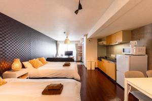 two beds in a small room with a kitchen at Rafaye N16 in Sapporo