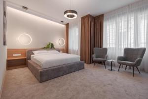 a bedroom with a bed and two chairs at Oasis Rooms Oradea in Oradea
