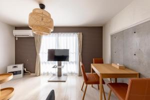 a living room with a dining room table and a television at Rafaye N16 in Sapporo