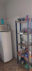 a kitchen with a refrigerator and shelves with food at Pousada e Pesqueiro Recanto do Peixe in Carmo do Rio Claro