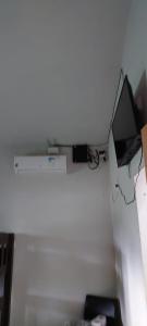 a room with a white wall with a television and a desk at Pousada e Pesqueiro Recanto do Peixe in Carmo do Rio Claro