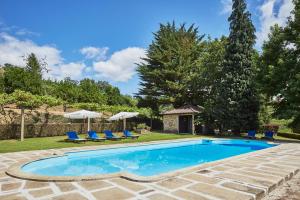 a swimming pool with blue chairs and umbrellas at Casa de Canedo in Celorico de Basto