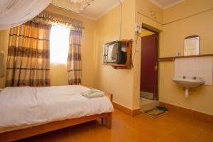 a small bedroom with a bed and a sink at Jamindas Paradise Motel in Kakamega