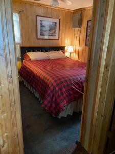 a bedroom with a bed with a red plaid blanket at Northwoods Lake Content Cabin in Saint Germain