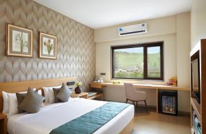 - une chambre avec un lit, un bureau et une fenêtre dans l'établissement Click Hotel, Junagadh, à Junagadh