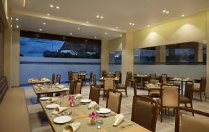 a restaurant with tables and chairs and a large screen at Click Hotel, Junagadh in Junagadh
