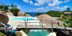 a swimming pool with a bench and a view of the ocean at Château de feuilles & SPA - Praslin island in Baie Sainte Anne