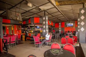 a restaurant with red chairs and a man sitting at a table at Hotel Nomad in Athi River