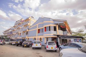 un grand bâtiment avec des voitures garées devant lui dans l'établissement Hotel Nomad, à Athi River