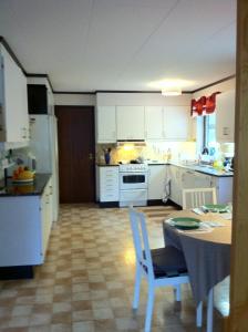 uma cozinha com armários brancos e uma mesa e cadeiras em Barbro 9 em Borlänge