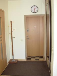 a hallway with a clock on the wall and a door at M. Mažvydo al. butas in Klaipėda