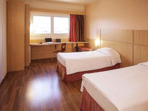 a hotel room with two beds and a desk with a laptop at ibis Uberlandia in Uberlândia