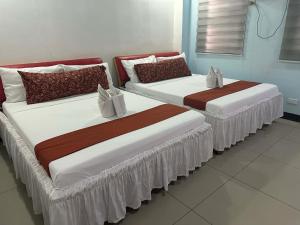 zwei Betten in einem Zimmer mit weißen und roten in der Unterkunft DBuilders Rooms Hotel in Sampong