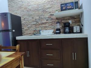 a kitchen with a sink and a brick wall at Chan Kiin Departamentos in Valladolid