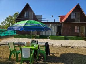 a green table with a blue umbrella and chairs at Amangarh Corbett Farmstay in Rehar