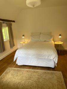 a bedroom with a white bed with two tables and two lamps at 3 bedroom remote rural idyll on the North Downs in Faversham