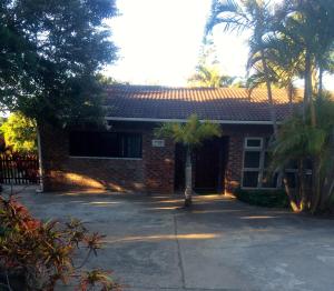 a brick house with a palm tree in front of it at Mopani Cottage in East London