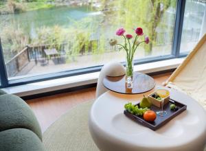 a table with a tray of fruit and a vase with flowers at Zhangjiajie National Park East Gate Happy Hotel-River View&City Center&Book Tickets&English Speaking&Free Laundry in Hanqiyu
