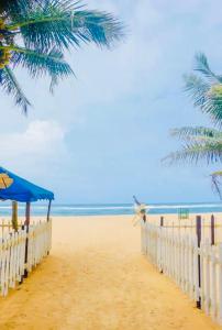 a sandy beach with a blue umbrella and palm trees at Scenic Lanka rooms in Dehiwala