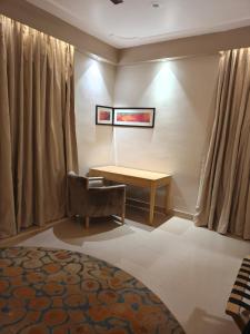 a bedroom with a bed and a table and a chair at Vijay Mansion Pratap Enclave in Jaipur +1 photo