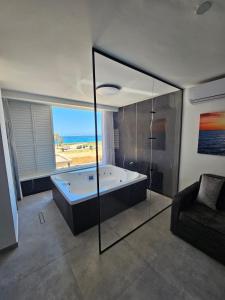 a large bathroom with a tub and a couch at חוויה בכיכר גולד in Netanya