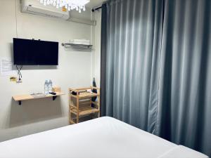 a bedroom with a bed and a tv and a curtain at Udomsuk Inn & Cafe - BTS Udomsuk in Bangkok +44 photos