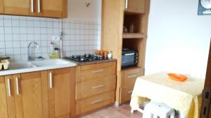 een keuken met houten kasten, een wastafel en een magnetron bij Appartement Vue Sur Mer Turquoise in Mahdia