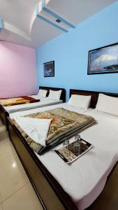 a group of three beds in a room at Hotel Aryaman in Haridwār