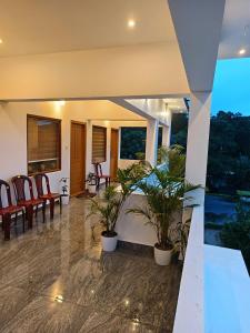 a porch with chairs and potted plants on it at Manjula Homestay in Vagamon