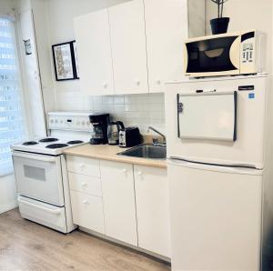 a kitchen with white appliances and a microwave at The Skyline Luxury Unit in Bélanger