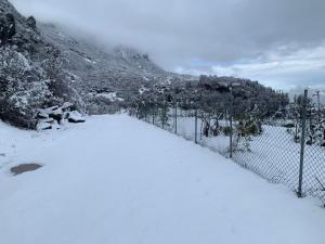 a fence covered in snow next to a mountain at Bujtina Shpella e Plakës Çerçan Librazhd in Librazhd