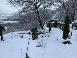 a person standing in the snow in front of a house at Bujtina Shpella e Plakës Çerçan Librazhd in Librazhd